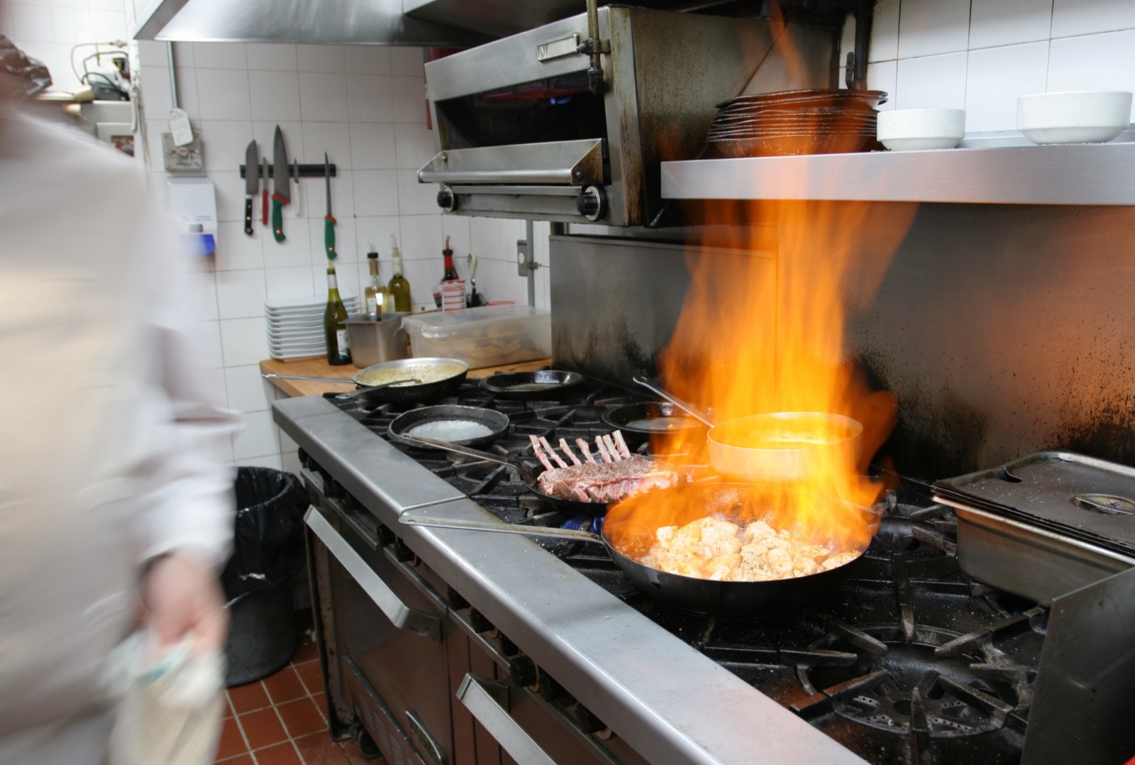 Flambage en poêle dans une cuisine professionnelle — photo d'illustration du métier, pas une photo de la maison